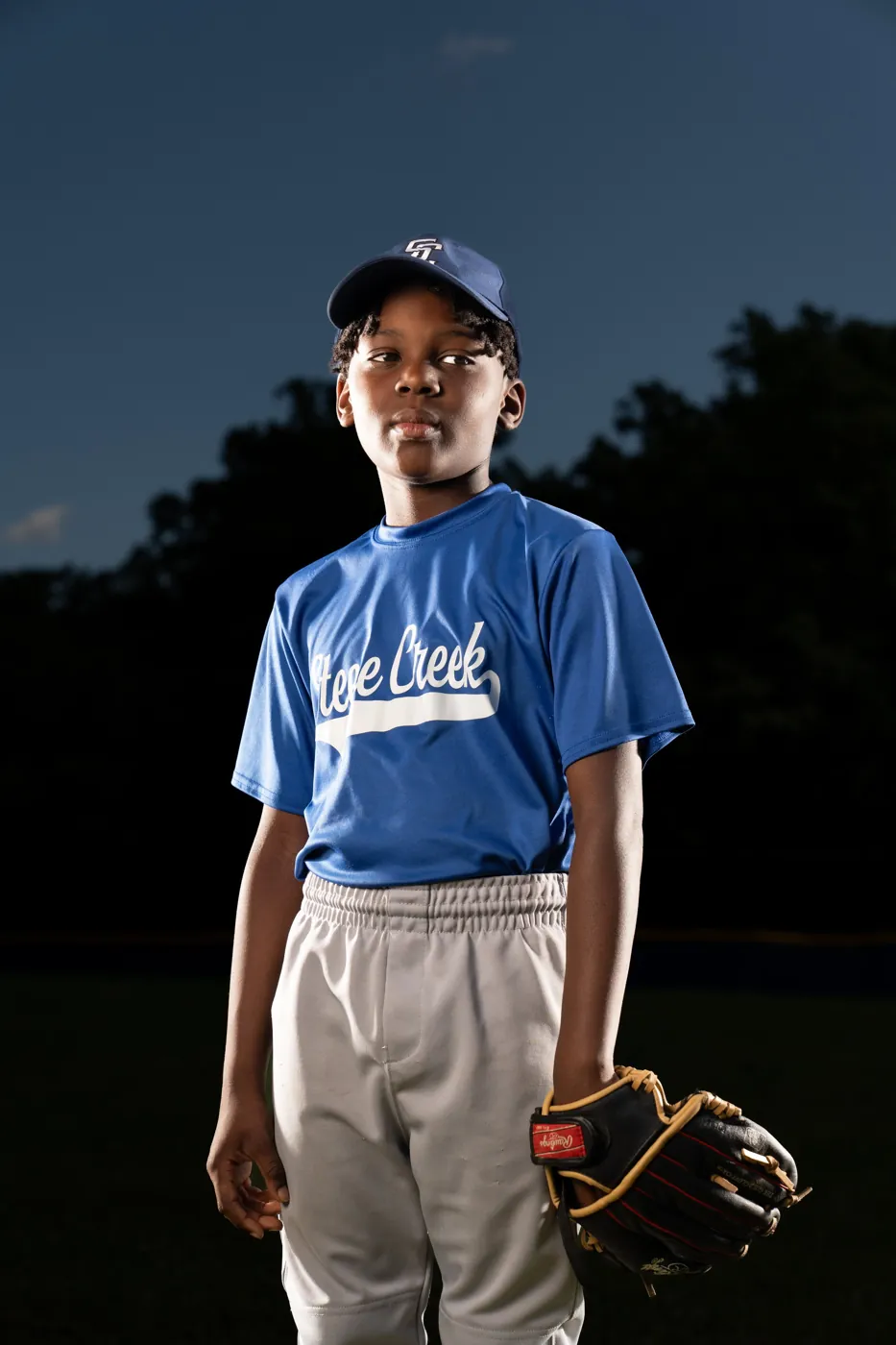 Young baseball player in a red jersey grinning with a glove raised